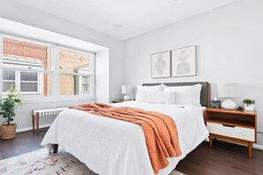 Relax in this serene bedroom with a large bed, two bedside tables, and a view of a nearby building.