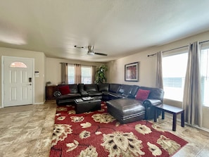 A living room with a sectional sofa, a coffee table, and a patterned rug.