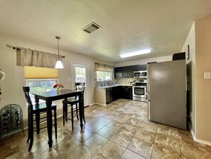 A compact kitchen with a dining area, a refrigerator, and a microwave.