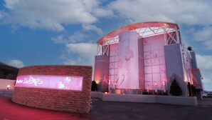 A modern building with a curved glass facade and a prominent display board in the foreground. - Restay SaKuRa - Adults Only (Hakodate)