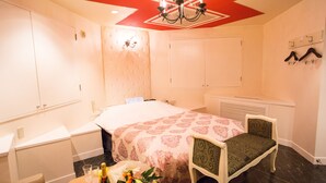 A hotel room with a bed, a chair, a table with a bottle and glasses, and a wall-mounted coat rack. - Restay SaKuRa - Adults Only (Hakodate)