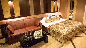 A hotel room with a bed, a sofa, a coffee table with a bottle and glass, and a mirror. - Restay SaKuRa - Adults Only (Hakodate)