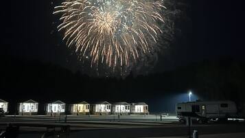 A nighttime scene with a large firework display over a row of small, uniformly lit houses.