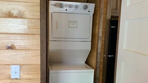 A compact laundry room with a Whirlpool washer and dryer, wooden walls, and a white door. - Tiny Homes for Rent, minutes to the Casino, Golf Course & Water Park.
 (Philadelphia)