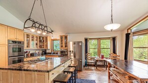 A modern kitchen with wooden cabinets, stainless steel appliances, and a large island with bar stools.