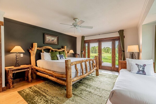 Ein Schlafzimmer mit hölzernem Bettgestell, einem großen Fenster und Blick auf eine grüne Landschaft.