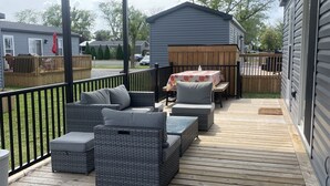 A covered outdoor deck with wicker furniture and a table, surrounded by a wooden fence. -  Niagara-on-the-Lake Cottage (Niagara-on-the-Lake)