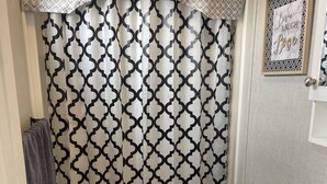 A bathroom with a patterned shower curtain, a toilet, a sink, and a small potted plant. -  Niagara-on-the-Lake Cottage (Niagara-on-the-Lake)