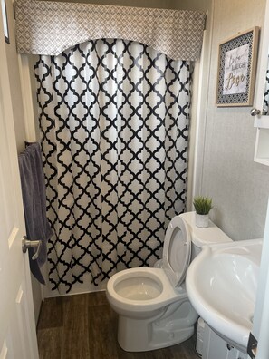 Compact bathroom with a modern design, featuring a toilet, sink, and shower area.