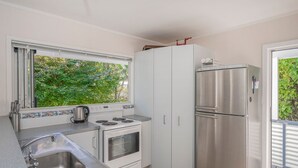 Una cuina compacta amb rentatge, fogó, forn i frigorífic d'acer inoxidable.