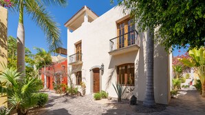 Une cour avec un chemin de pierre, des palmiers et un bâtiment doté de balcons et de fenêtres.