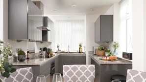 Una cocina moderna con armarios grises, una isla central y un comedor con sillas estampadas.