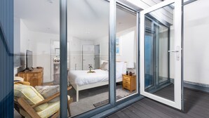 Un dormitorio moderno con un amplio ventanal corredero que da a un balcón.