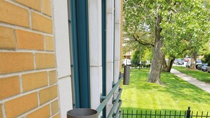 A building with a brick facade, a metal railing, and a grassy area with trees. - Cozy 1-2 BR APT w/fireplace & Patio/Deck (Chicago)