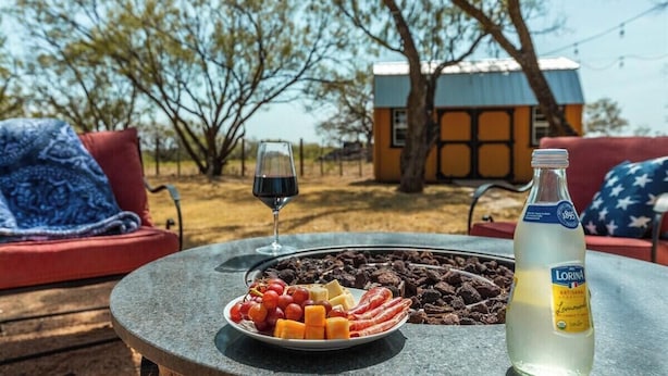 A table with a plate of food, a bottle of liquor, and a wine glass.