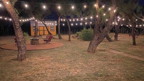 An outdoor area with string lights, a small building, and a fire pit.