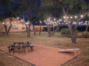 Une cour arrière avec une table de pique-nique, des guirlandes lumineuses et une maison en arrière-plan.