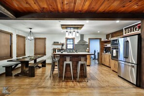 A modern kitchen with a central island, wooden flooring, and stainless steel appliances.