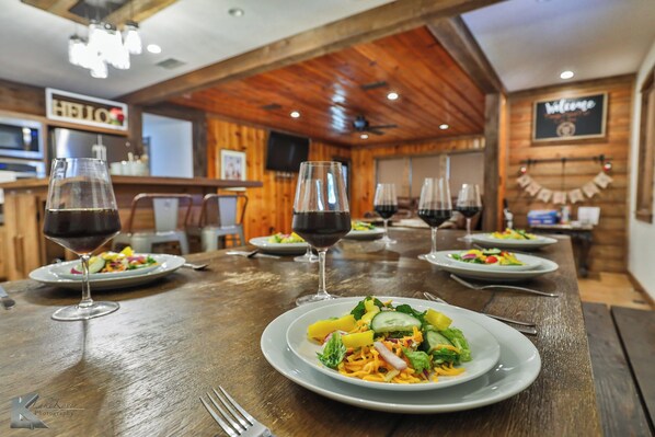 Enjoy a warm and inviting dining experience with tables set for a meal, flat-screen TV, and a modern chandelier.