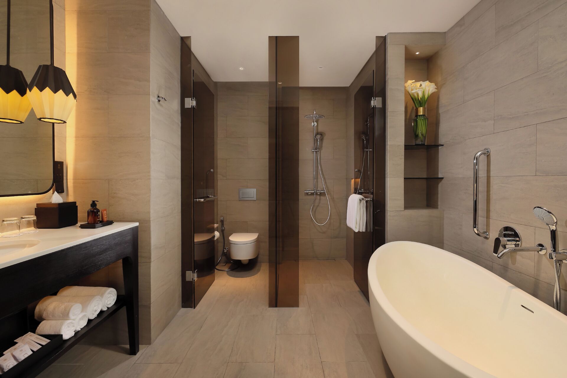 Ein modernes Badezimmer mit einer großzügigen Badewanne, einer separaten Duschkabine und einem Waschtisch mit Spiegel und Handtuchhalter.