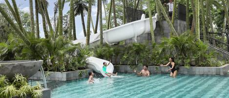 A water park with a slide, palm trees, and a pool.