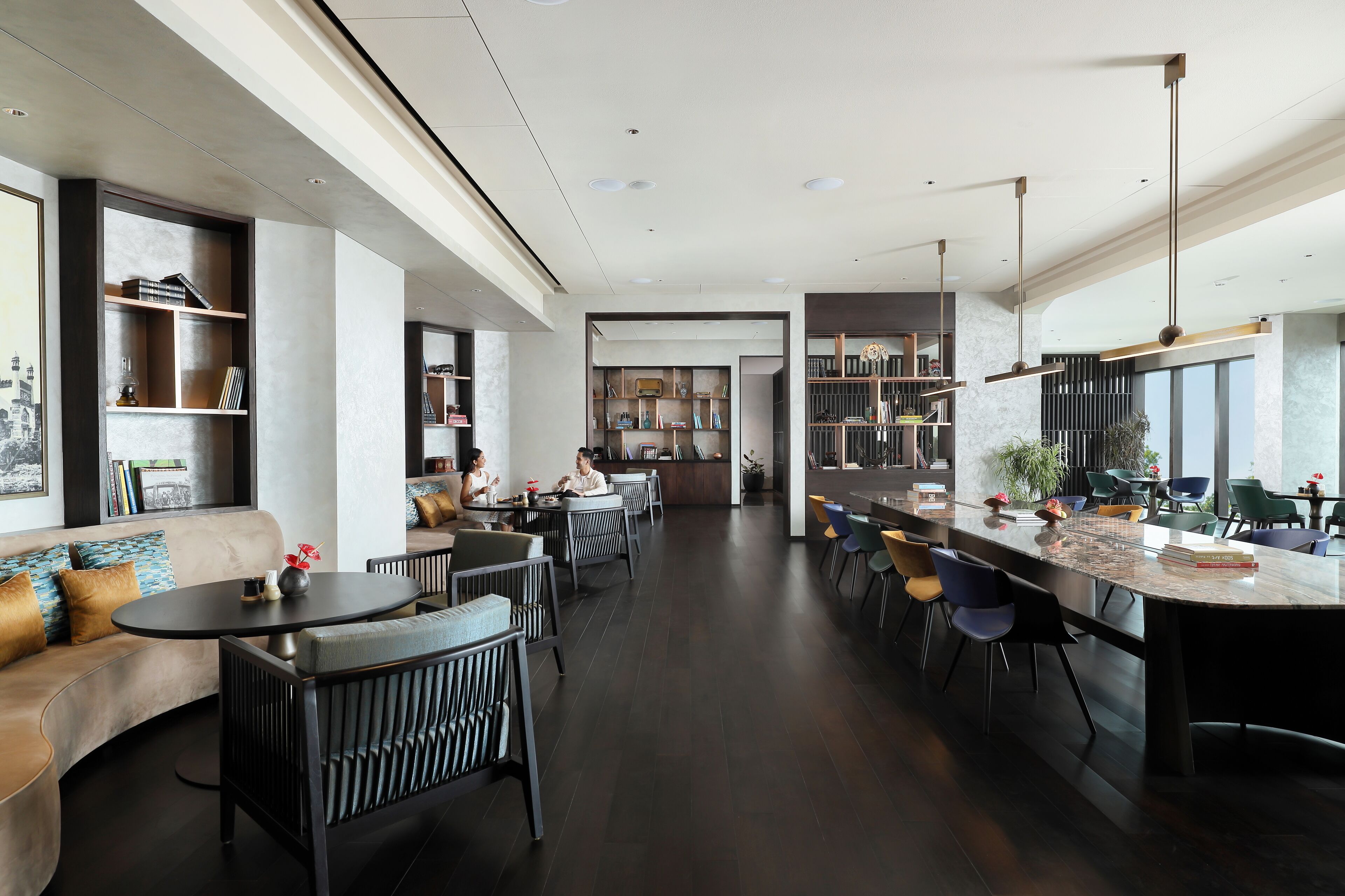 A modern interior with a dining area, bar, and seating with bookshelves.