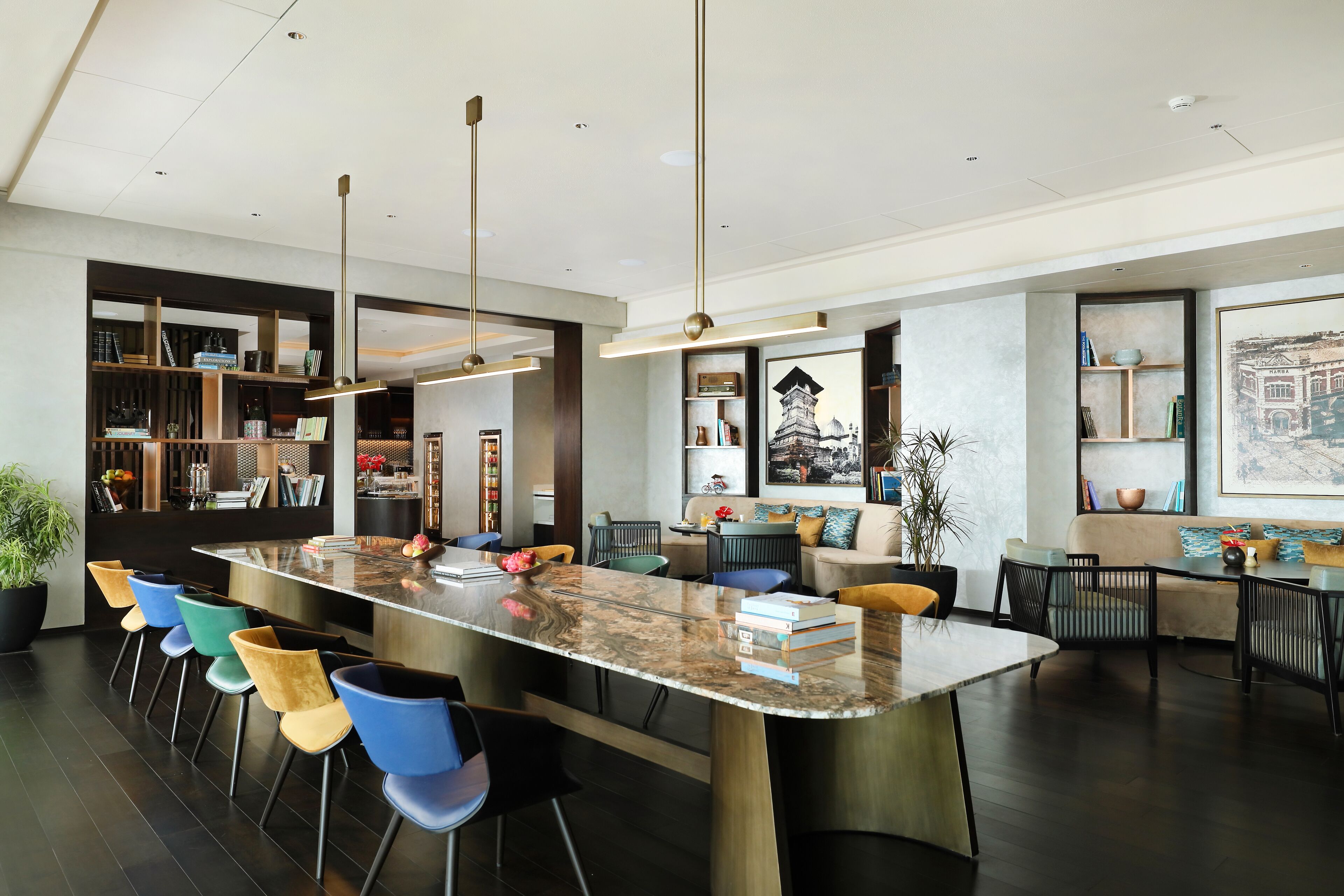 A modern kitchen with a marble island, bar stools, and pendant lighting.