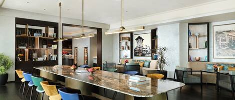 A modern kitchen with a marble island, bar stools, and pendant lighting.