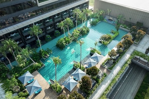 An aerial view of a hotel with a swimming pool surrounded by lush greenery, multiple balconies, and outdoor seating areas. - Padma Hotel Semarang (Semarang)