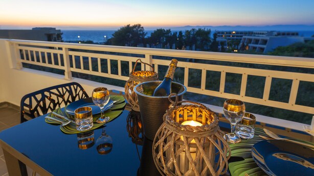 Mesa lista para cenar con vista al océano al atardecer.
