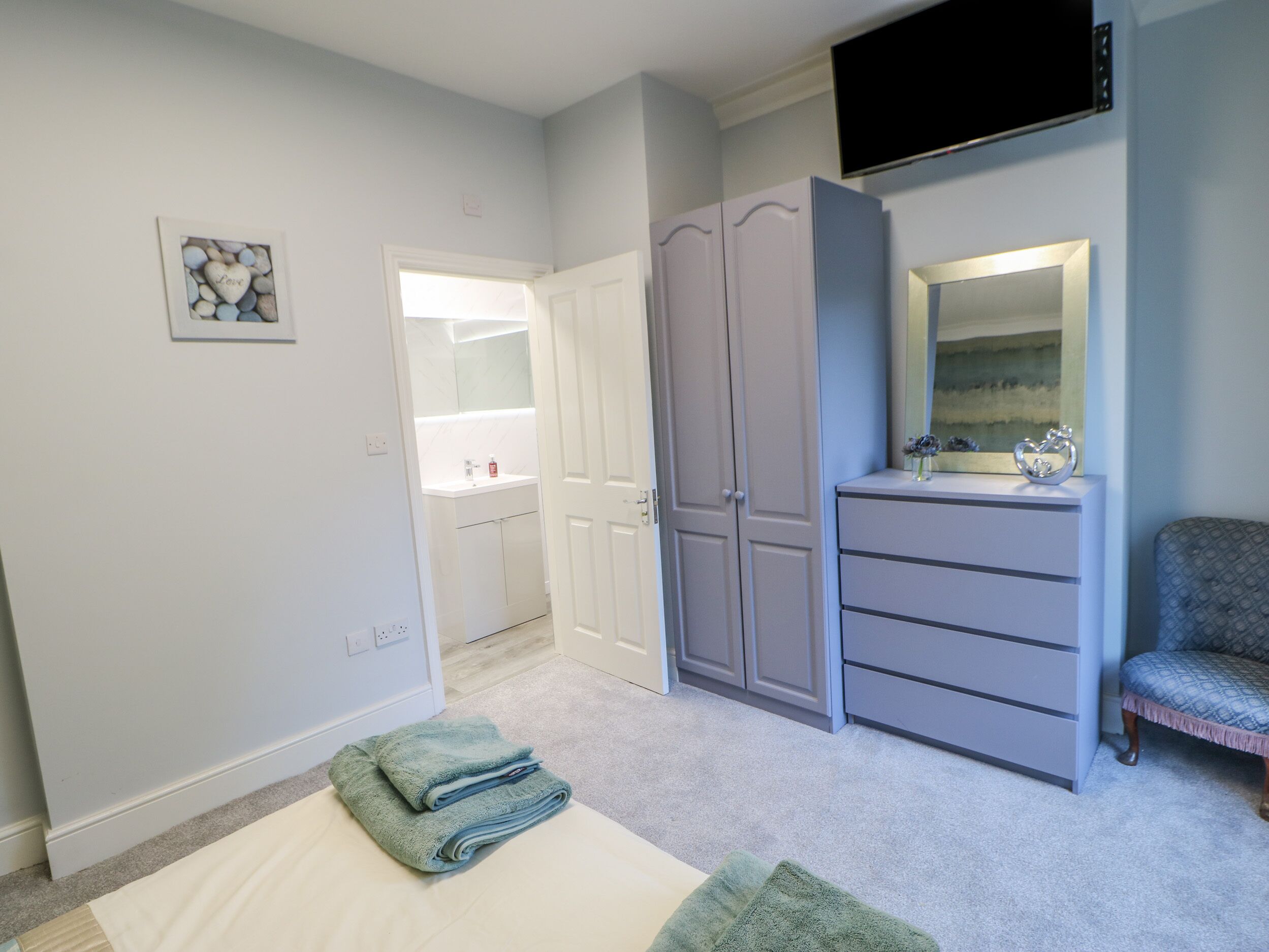 Un dormitorio con cama, cómoda, tocador y televisor.