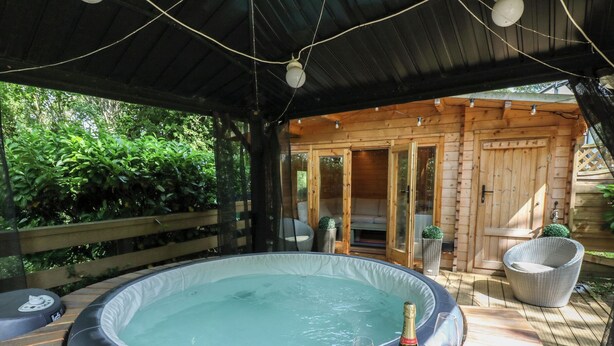 A hot tub with a bottle of champagne and glasses on a wooden deck.
