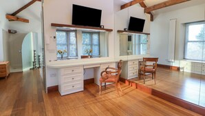 A spacious room with a large mirror, wooden beams, a desk, and a chair.