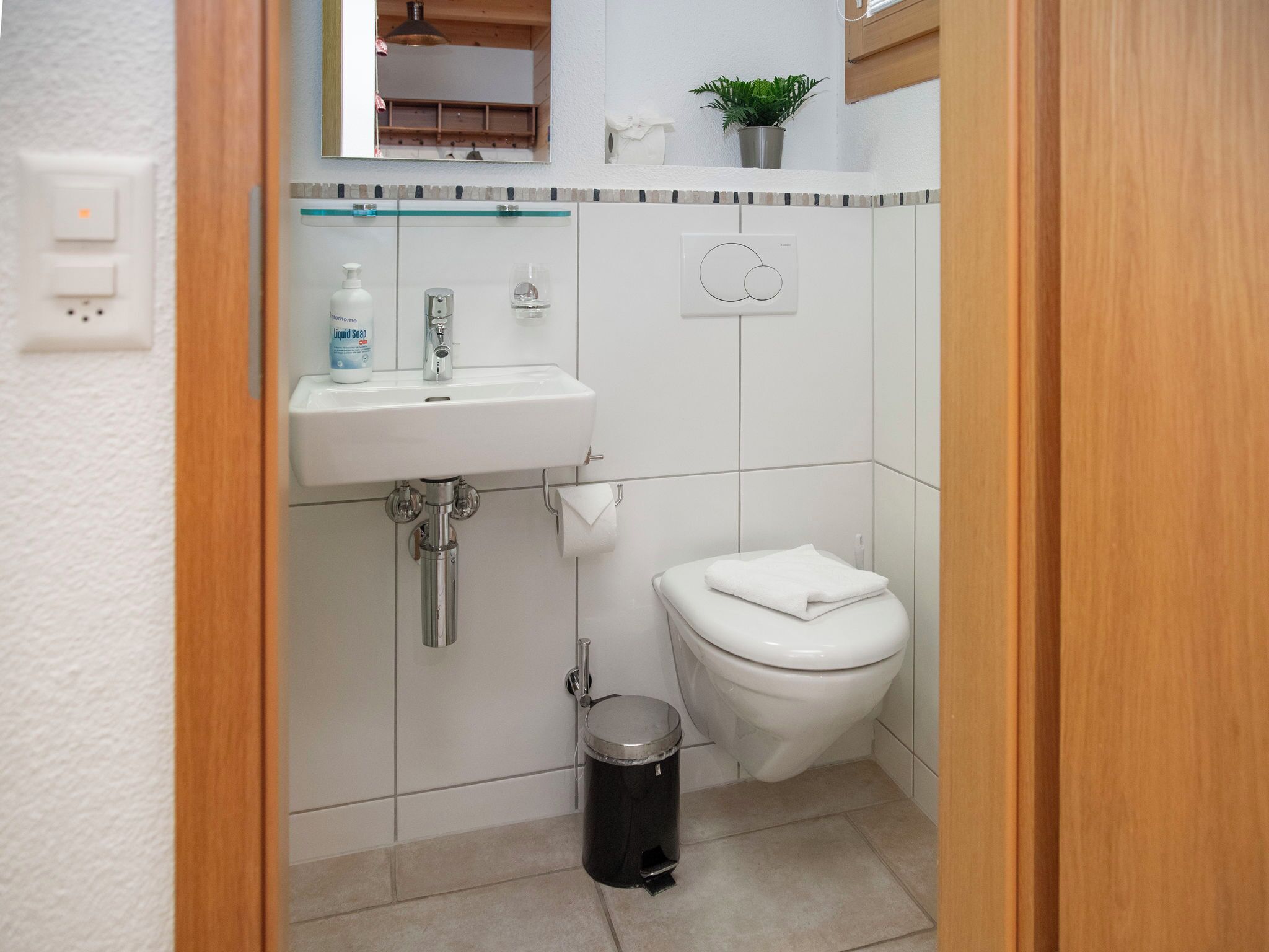 Un baño pequeño con un lavamanos blanco, un inodoro y un cesto de basura.