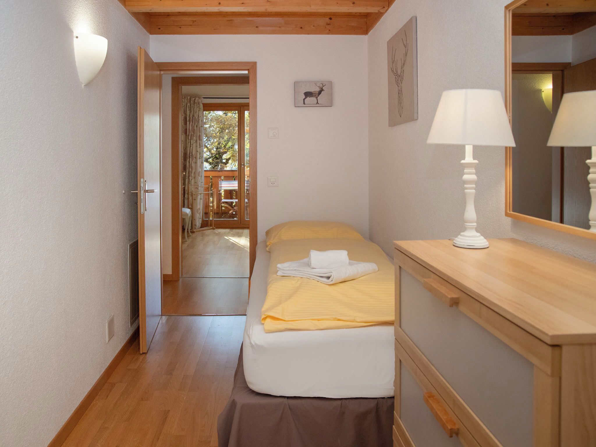 Une chambre à coucher comprenant un lit, une table de chevet, une lampe et une porte donnant sur un balcon.