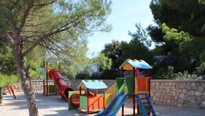 Un parque infantil con un tobogán rojo, un tobogán azul y una estructura para escalar.