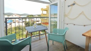 Un balcón con mesa y sillas, vistas del entorno y un tapiz decorativo.