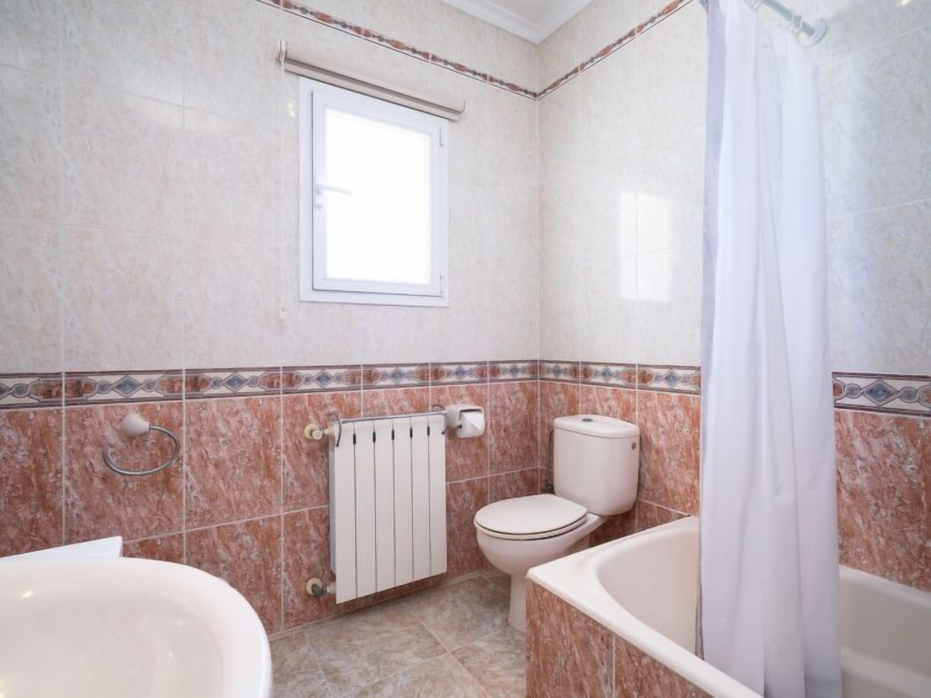 Un baño con inodoro, bañera y ventana.
