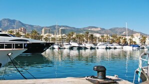 A marina with boats docked, palm trees, and buildings in the background. - Villa Juna by Interhome (Benalmádena Costa)