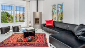 A modern living room with a black leather sofa, a glass coffee table, and a colorful rug. - Villa Juna by Interhome (Benalmádena Costa)
