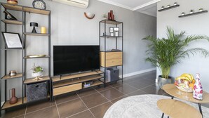 A modern living room with a flat-screen TV, built-in shelves, a potted plant, and a dining area with a table and chairs. - ✩ direct beach location ✩ family friendly ✩ Netflix (Santa Pola)