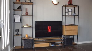 A living room with a flat-screen TV, wooden shelves, and a black entertainment unit. - ✩ direct beach location ✩ family friendly ✩ Netflix (Santa Pola)
