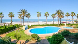 A pool area with palm trees and a view of the beach.