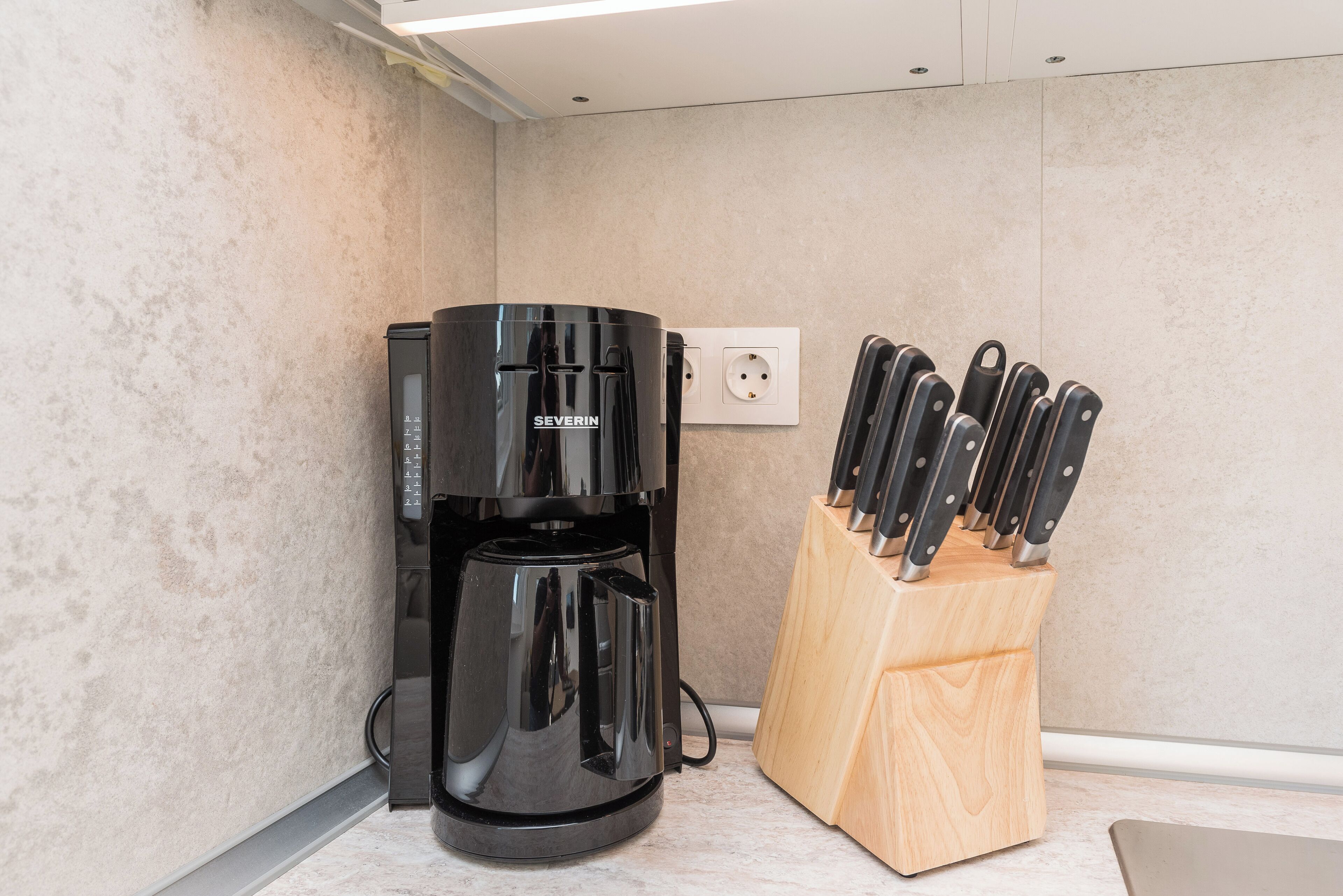 A coffee maker and a knife block in a kitchen area.