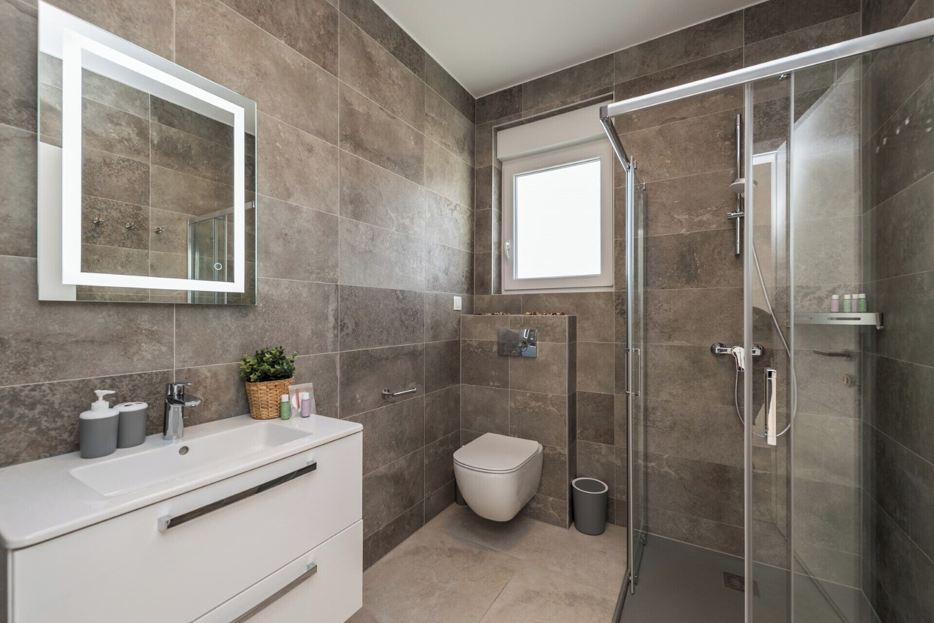 A modern bathroom with a glass shower enclosure, a white vanity with a mirror, and a toilet.