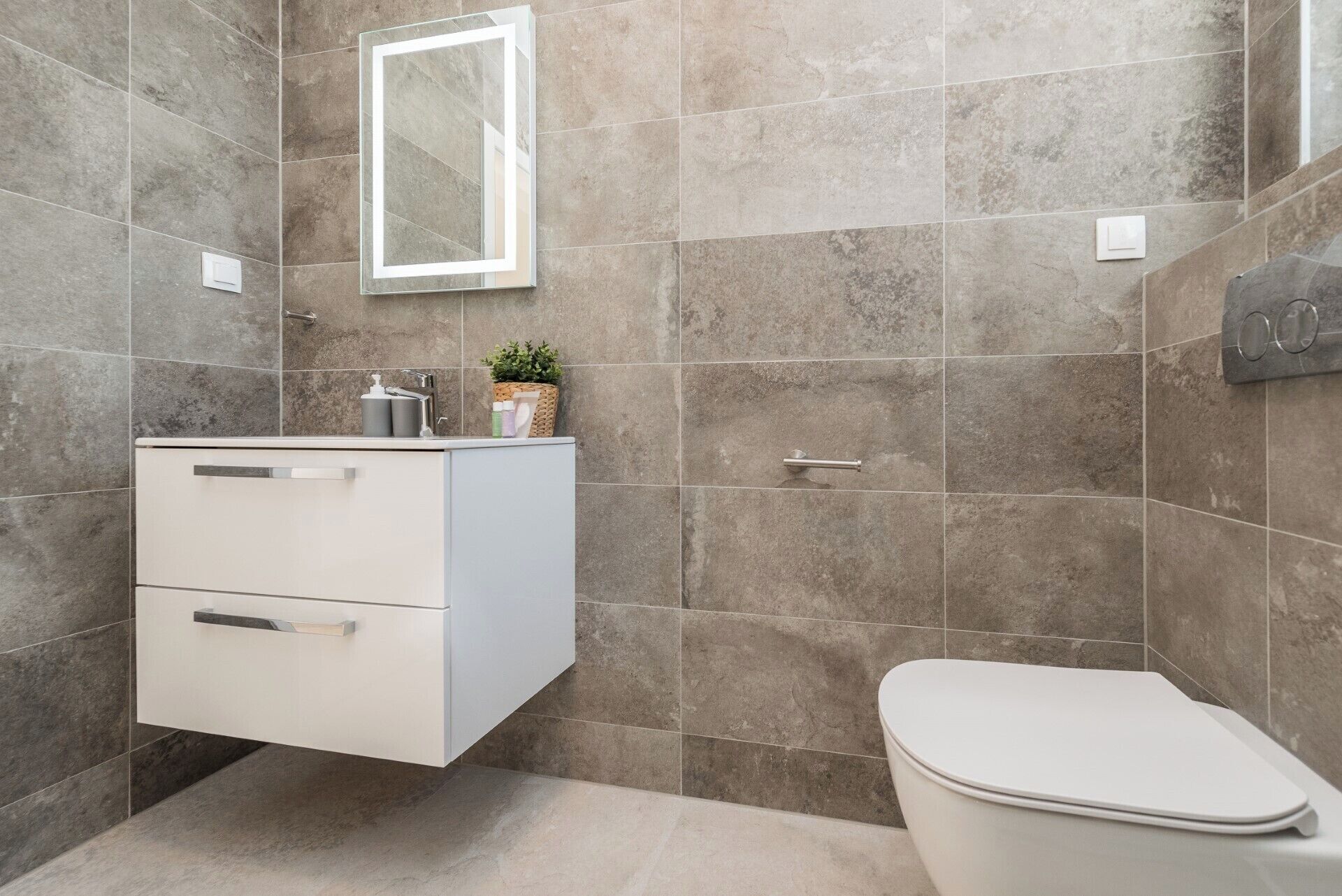 A modern bathroom with a white vanity, a toilet, and a mirror.