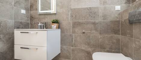 Un baño moderno con tocador blanco, inodoro y espejo.