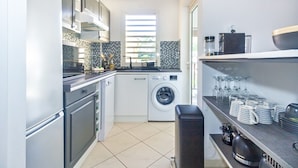 Una cocina compacta con lavadora, un lavamanos y una encimera con utensilios de cocina.