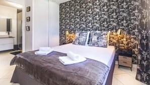Un dormitorio con cama, dos lámparas de noche, una mesita de noche y una pared con estampado floral.