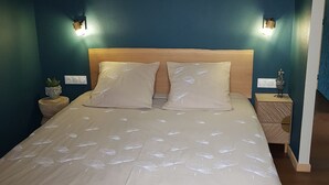 Un lit avec une tête de lit, deux tables de chevet et des lampes fixées au mur.